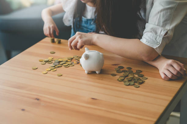 Mother and her daughter count coins from piggy bank Young Asian Mother and her daughter count coins from piggy bank. counting coins stock pictures, royalty-free photos & images