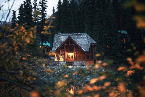 wooden lodge illumination with autumn leaves on emerald lake at yoho national park - cottage autumn wood woods imagens e fotografias de stock