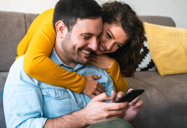istock Cheerful couple using mobile phone at home stock photo 1252471429