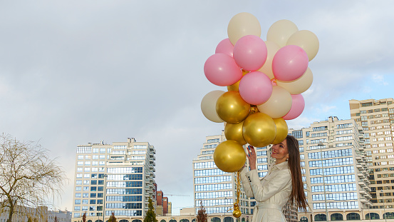 Happy woman with balloons on the background of the building. Celebration on nature outdoors.
