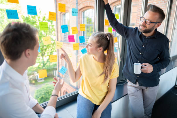 Young creative business people meeting at office. Business people meeting at office and use post it notes to share idea. Brainstorming concept. Sticky note on glass wall. office fun business adhesive note stock pictures, royalty-free photos & images