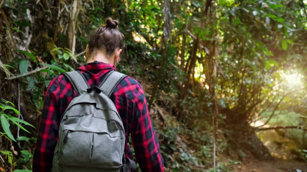 istock young woman with backpack walks in lush tropical forest 1252483465