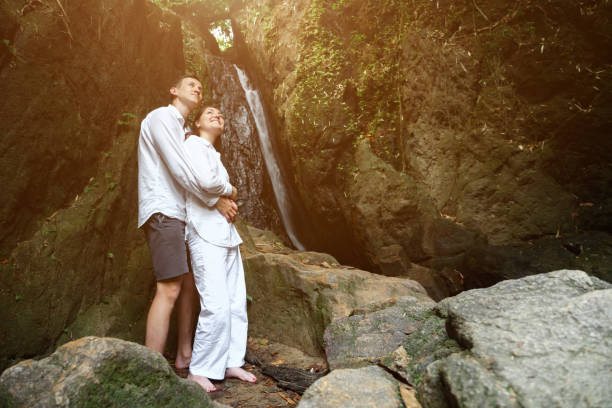 istock happy couple stands against tropical waterfall 1252483475