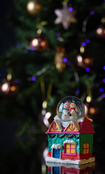 istock Christmas scene with tree, lights and snow globe. Selective focus on black background. 1252486499