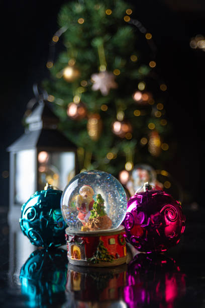 istock Christmas scene with tree, lights and snow globe. Selective focus on black background. 1252486501