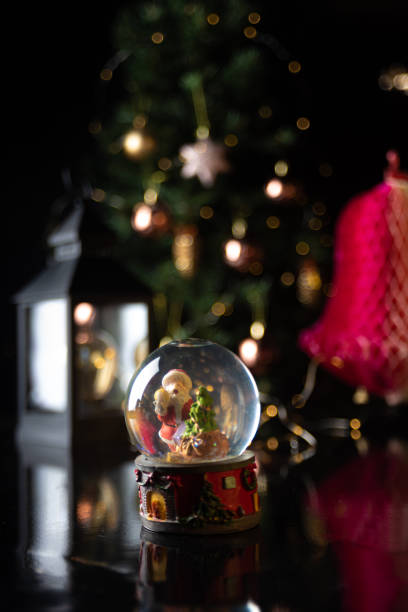 istock Christmas scene with tree, lights and snow globe. Selective focus on black background. 1252486513