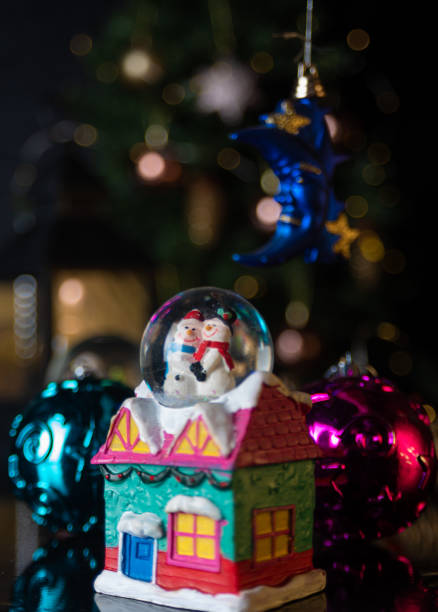 istock Christmas scene with tree, lights and snow globe. Selective focus on black background. 1252486514