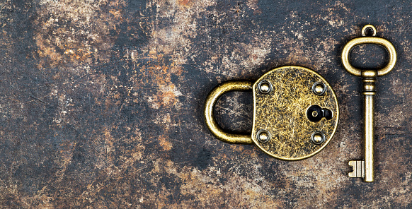 Escape room concept, vintage gold key and locked padlock