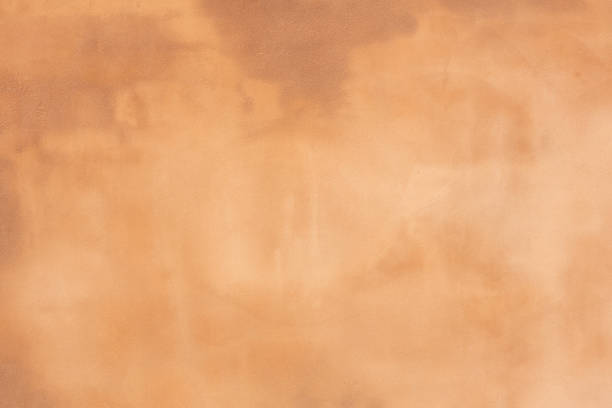 istock Rustic orange brown earth toned concrete cement wall with darker and lighter areas to use as a background or banner 1252491393