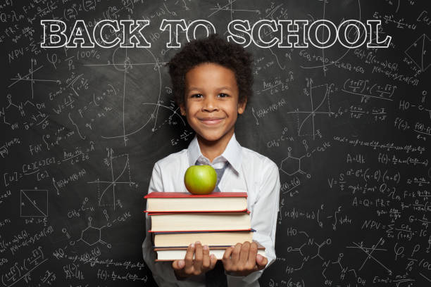 istock Smiling child in classroom on blackboard background with science formulas 1252494225
