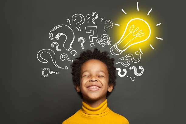 istock Happy black kid on black background with light bulb and question marks. Brainstorming and idea concept 1252494227