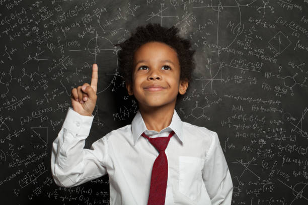 istock Black kid student pointing at science formulas on chalkboard 1252494252