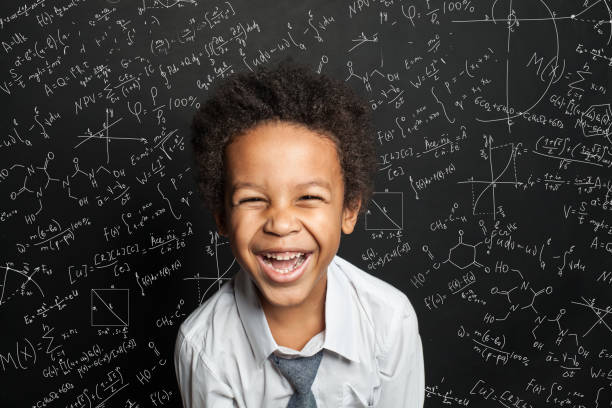 istock Black child student laughing against chalkboard background with science formulas 1252494253