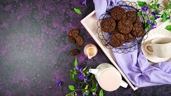 Serving freshly baked double chocolate chip homemade cookies on pink tray with tea and coffee, creative concept flat lay. Top view overhead with negative copy space.