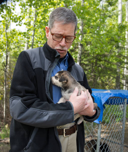 istock Senior Man Holds Husky Puppy 1252502650