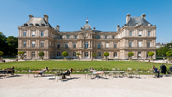 Paris : Jardin du Luxembourg with Senate in background. People sunbathing in foreground. There are not many people for a sunny day, because of Coronavirus Covid 19, tourists are not come back. Paris in France. June 22, 2020