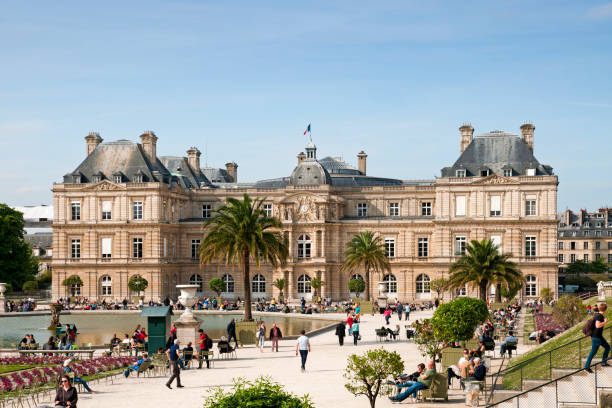 Paris : Jardin du Luxembourg with Senate in background. People walking or having a break in foreground . Paris in France. April 18, 2019