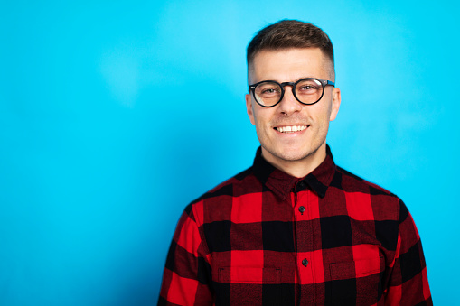 Studio portrait of a young man posing against blue background.