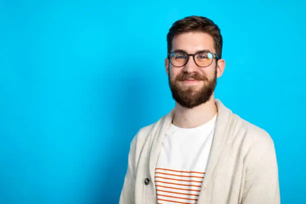 Photo of Young Caucasian man posing against blue background