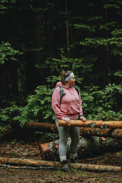 istock Spending the Day in Nature: a Plus Size Woman in a Pink Sweatshirt Wearing a Backpack While Hiking in the Forest 1252521198
