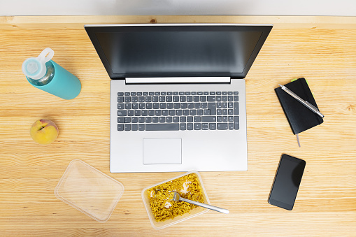 top view of a workspace with a laptop, phone and lunch box with rice, concept of fast food in the office