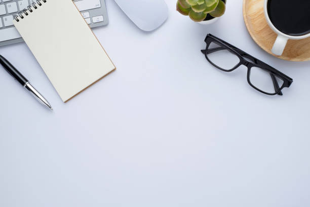 istock Top view above of White office desk table with keyboard, notebook and coffee cup with equipment other office supplies. Business and finance concept. Flat lay with blank copy space. 1252528543