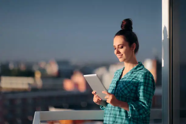 Photo of Woman in Pajamas with Pc Tablet Standing in Balcony