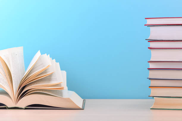 istock The book is open, the sheets are fan-shaped on a blue background next to a stack of books. 1252566645