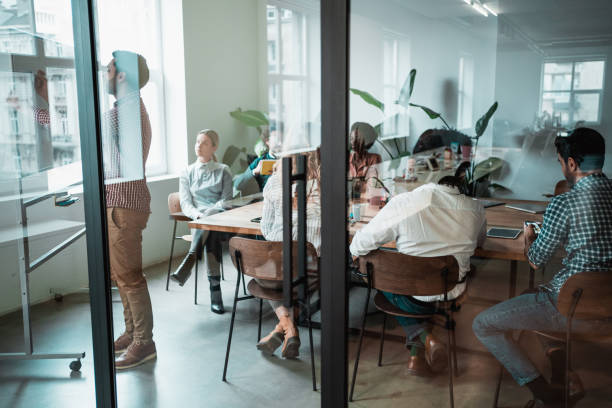 young entrepreneur presenting his coworkers new business strategy on a meeting. - estúdio de design imagens e fotografias de stock