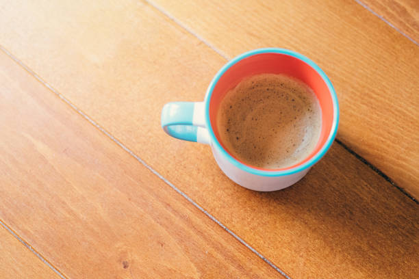 Above view of coffee cup with hot aromatic coffee placed on a wooden table.