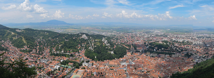 Panorama view of the old center of Brasov in Romania during a summer sunset with amazing light. Old houses with orange brick roofs