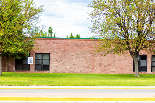 In Western Colorado School Building During Summer Time with Green Grass and Driving Lane in Foreground (Shot with Canon 5DS 50.6mp photos professionally retouched - Lightroom / Photoshop - original size 5792 x 8688 downsampled as needed for clarity and select focus used for dramatic effect)