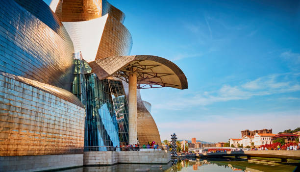 Panoramic view of the Guggenheim Museum, designed by ‬Frank Gehry, Nervion river, Bilbao, Spain Bilbao, Spain - September 24, 2017: Panoramic view of the Guggenheim Museum, designed by ‬Frank Gehry, on the bank of Nervion river. A famous and very popular place for worldwide tourism which has boosted Bilbao's economy with its astounding success. The Guggenheim Museum is a fusion of ‬swirling forms that responds to an intricate program and an industrial and urban context‭. frank gehry building stock pictures, royalty-free photos & images