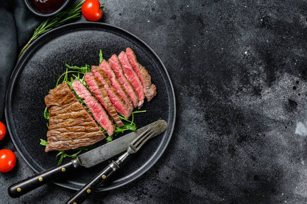 플랫 아이언 스테이크를 구워 서 잘라. 대리석 쇠고기 고기. 검은 색 배경. 맨 위 보기입니다. 복사 공간 - steak close up grilled skirt steak 뉴스 사진 이미지