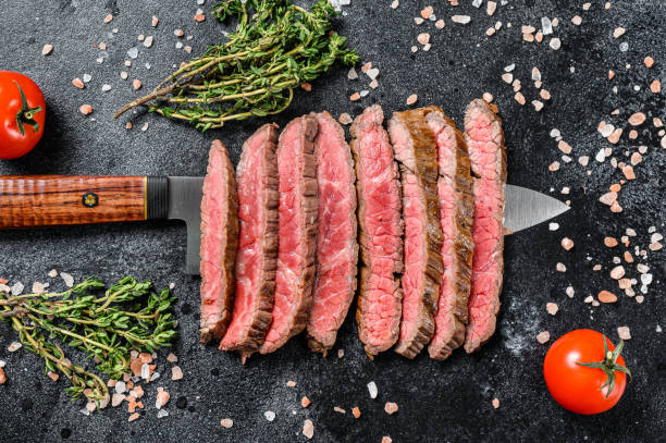 Grilled and sliced Flank rare steak. Marble beef meat. Black background. Top view Grilled and sliced Flank rare steak. Marble beef meat. Black background. Top view. flank steak stock pictures, royalty-free photos & images