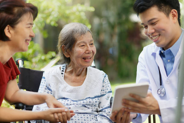 médico asiático hablando con paciente de edad avanzada en silla de ruedas - asiático de asia sudoriental fotografías e imágenes de stock