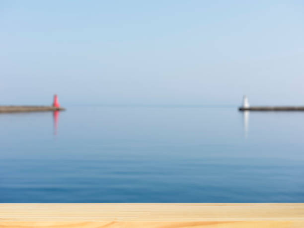 Blank wood table top against blurred sea and lighthouse with copy space,