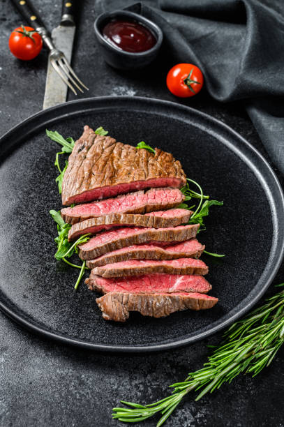 istock Grilled and cut flank steak. Marble beef meat. Black background. Top view 1252587696