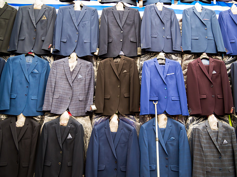 Rows of hanging new men's suits on the market.