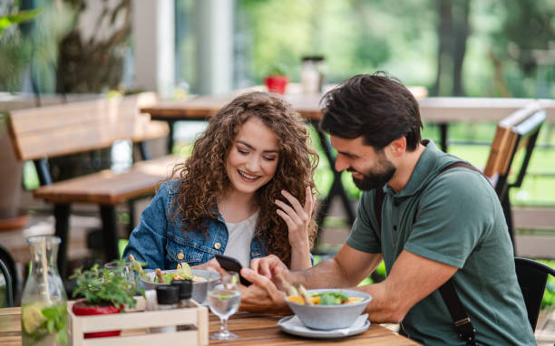 istock Happy couple sitting outdoors on terrace restaurant, using smartphone. 1252592542