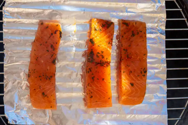 Seasoned raw salmon fish steaks on foil on a grill ready for cooking viewed from overhead