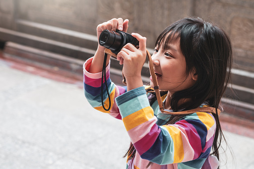 Asian child girl with a colorful T-shirt is smiling and taking pictures happily.