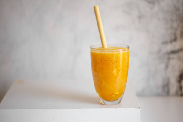 istock Tasty peach smoothie in glass on white table 1252597596