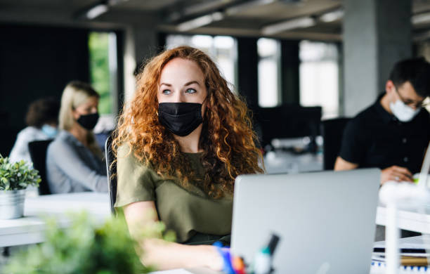 istock Young woman with face mask back at work in office after lockdown. 1252597749