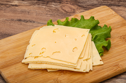 Sliced yellow cheese over salad leaves