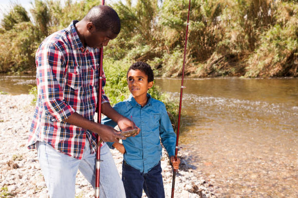 istock Man and boy holding fish on rod 1252601291