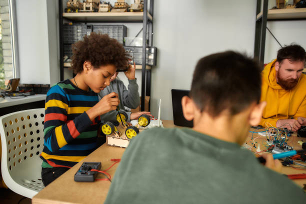 istock Learning never exhausts the mind. Boy using screwdriver while fixing bolts on a robot vehicle. Smart kids and STEM education. 1252602809