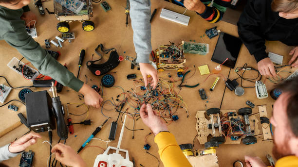 istock Bringing your ideas and innovations to life. Happy children working with wires, constructing diy robot in class. Smart kids and STEM education. 1252604545