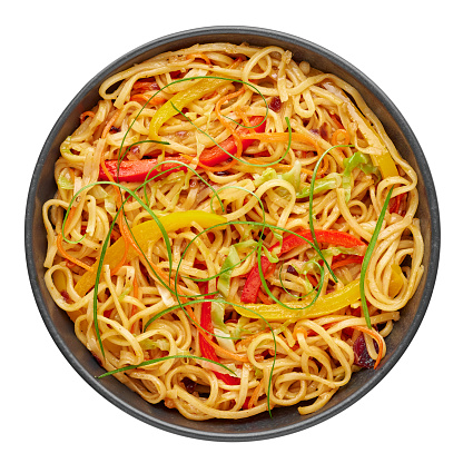Chilli Garlic Hakka Noodles in black bowl isolated on white background. Indo-Chinese vegetarian cuisine dish. Indian veg noodles with vegetables. Classic Asian meal