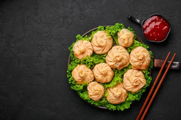 Photo of Veg Momos on black slate table top. Momos is the popular dish of indian, tibetan, chinese cuisines. Asian food. Vegetarian meal. Copy space. Top view
